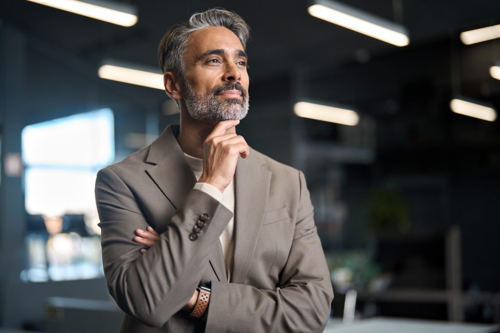 Middle aged business man investor standing in office thinking on question.