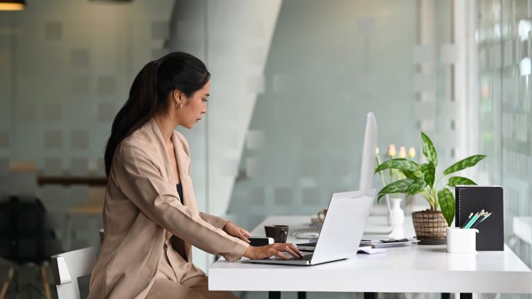 Side view of young professional female manager working on laptop at her office.